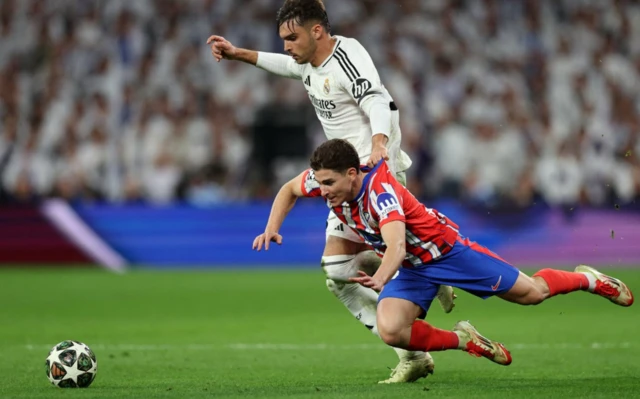 Real Madrid's Raul Asencio in action with Atletico Madrid's Julian Alvarez