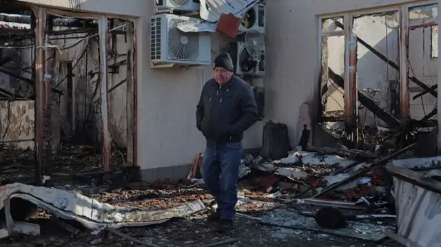 A man stands among debris in the courtyard of a building destroyed after a drone attack in Odesa