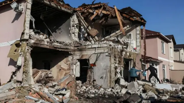 Residents carry out items from a house partly destroyed by a Russian drone strike