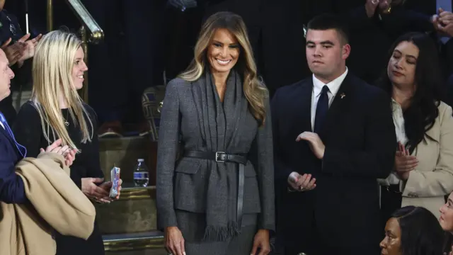 Melania Trump smiling in Congress while people around her clap