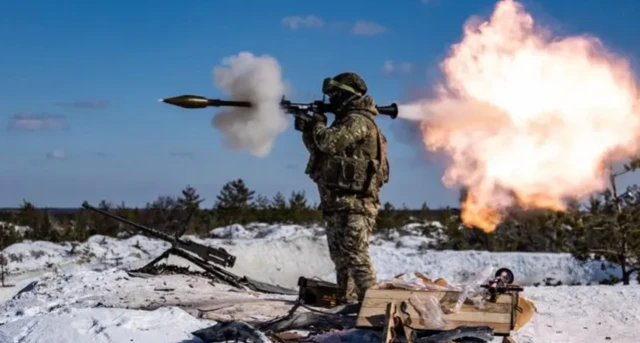 A soldier fires a missile on the battlefield in Ukraine. Snow can be seen on the ground and a fireball from the launched missile is seen behind the soldier