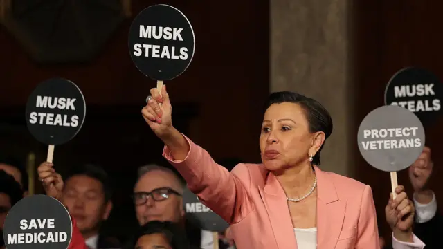 U.S. Rep. Nydia Velazquez (D-NY) holds a protest sign with fellow Democrats as U.S. President Donald Trump address a joint session of Congress