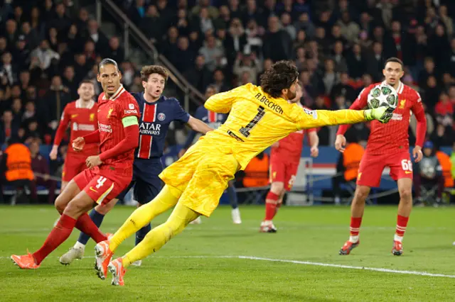 Alisson (C) dives to punch the ball