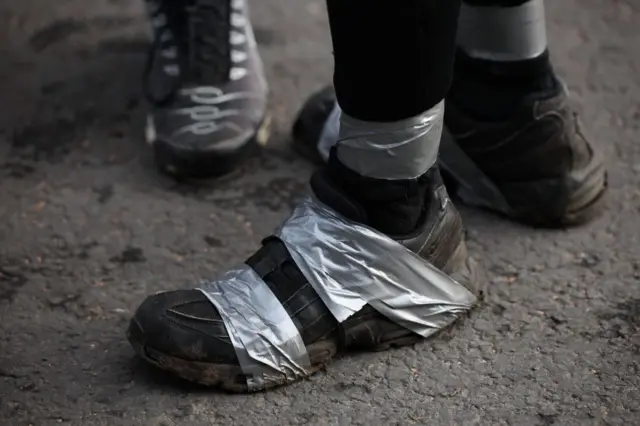 A shoe with silver tape wrapped around the foot and ankle