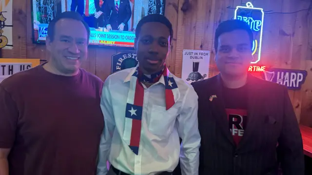 Three men in a bar smiling