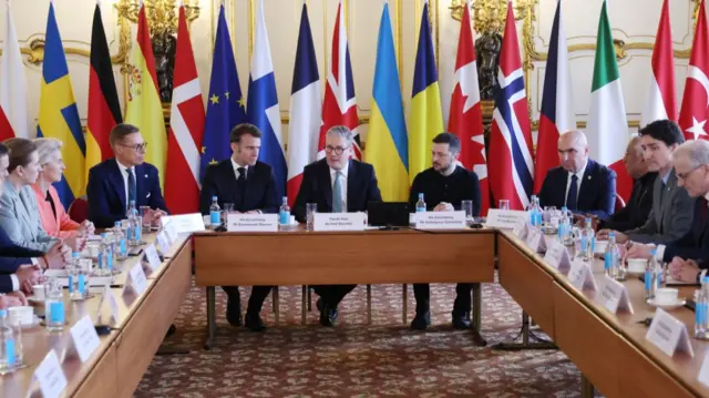 Britain's Prime Minister Keir Starmer (C), French President Emmanuel Macron (C-L), and Ukraine's President Volodymyr Zelensky (R) attend a plenary meeting as European leaders gather for a summit on Ukraine at Lancaster House in London. Flags of nations including Sweden, Germany, Denmark, Finland, France, UK, Ukraine, Romania, Canada, Norway, Italy and Poland stand behind the table of leaders