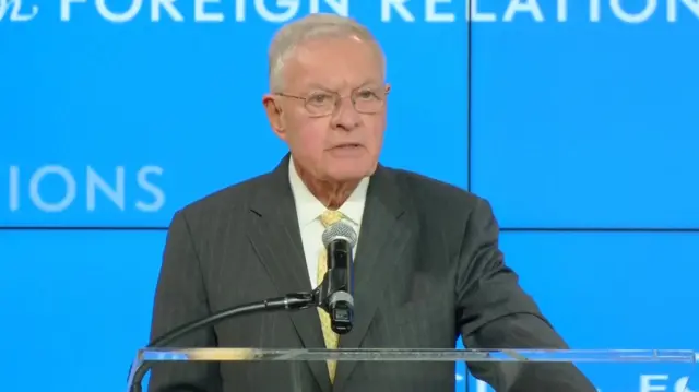 Keith Kellogg stands behind a podium with a microphone wearing a suit.