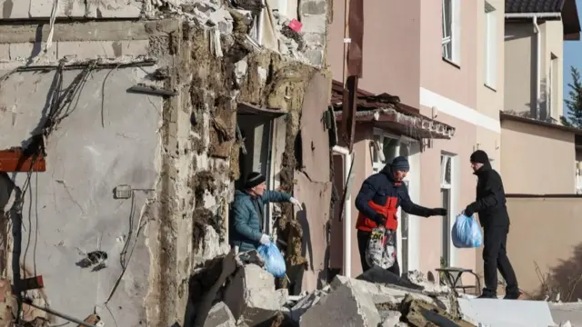 Residents carry out items from a house hit by a Russian drone strike