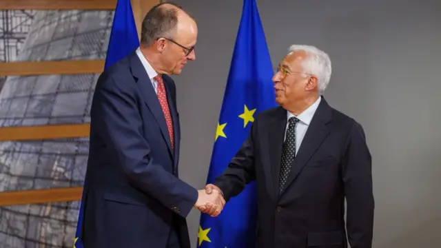 Costa shaking hands with Merz in front of two EU flags