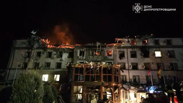 A heavily damaged building in Kryvyi Rih with flames from an ongoing fire visible in the top left of the bombed out building