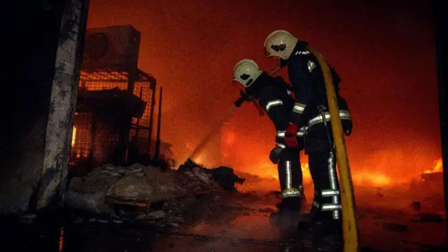 Firefighters work at the site of a warehouse hit by a Russian drone strike, amid Russia's attack on Ukraine, in Sumy