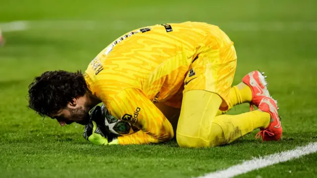 Alisson Becker holds on to the ball