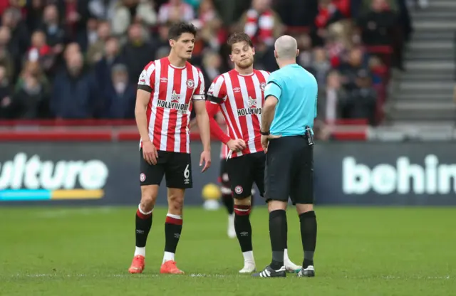 Christian Norgaard and Mathias Jensen speaking to referee Paul Tierney