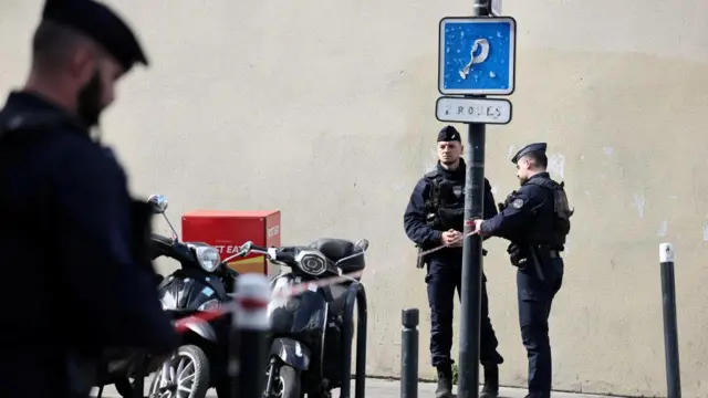 Three French police secure an area in Paris on a street.