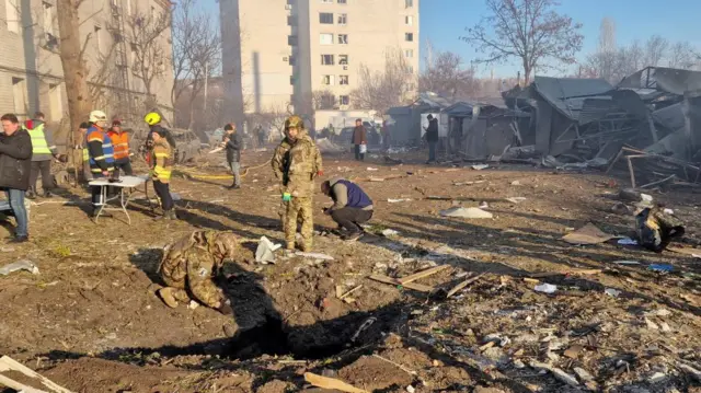 Police experts and rescuers work at a site an apartment building hit by a strike