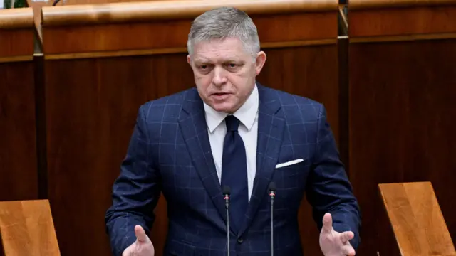 Robert Fico stands mid-speech talking into two microphones with his hands gesturing outwards