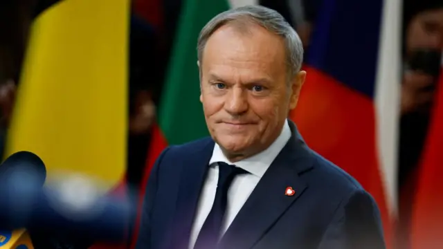 Polish Prime Minister Donald Tusk wears a blue suit with a red heart pinned on the lapel