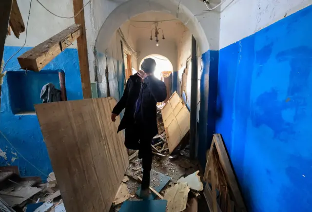 A man walks inside a damaged residential building