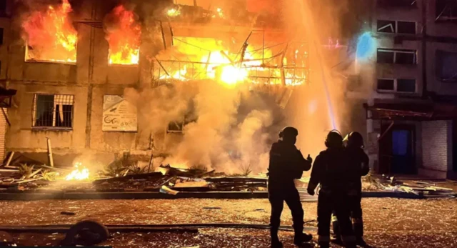 Ukraine's state emergency service released this photo of rescuers at the scene of the attack. Three firefighters can be seen spraying a building on fire with water coming out of a hose. Debris lies scattered around them