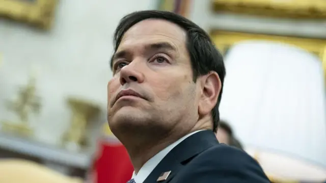 Close up shot of Marco Rubio looking to his left while he sits in the Oval Office