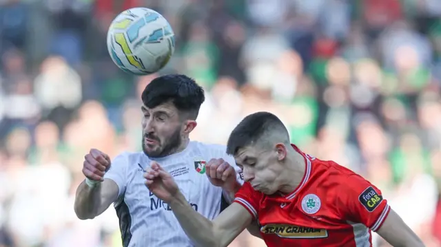 Glentoran's Daniel Amos in an ariel duel with Shea Kearney