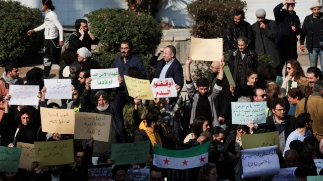 Protestors in Damascus holding signs in Arabic