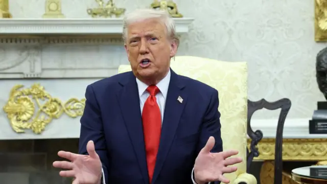 Trump speaking with his mouth open with his hands in front of him holding them out with his fingers splayed