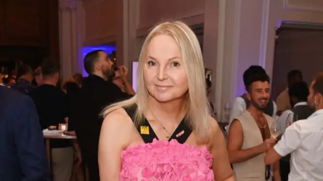 Willoughby in a pink dress, looking into the camera