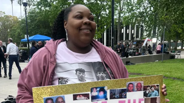 Evonna McIntosh holds a sign featuring pictures of the Menendez brothers