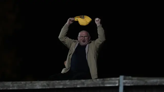A Leeds fan watches his side take on Oxford United from over the fence at on end of the Kassam Stadium