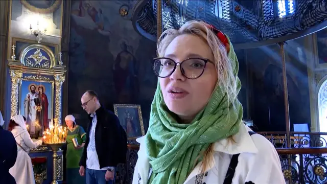 Oleksandra attends Easter morning service at church. She wears a green scarf around her head