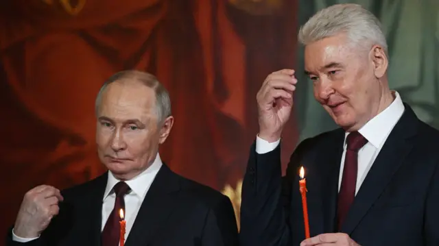 Vladamir Putin and Sergei Sobyanin hold a red lit candle
