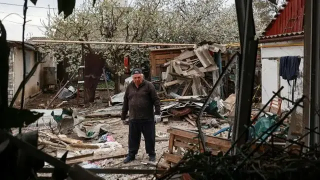 alt="A resident stands on a backyard of his house damaged during a Russian drone strike, amid Russia's attack on Ukraine, in Odesa, Ukraine April 16, 2025"