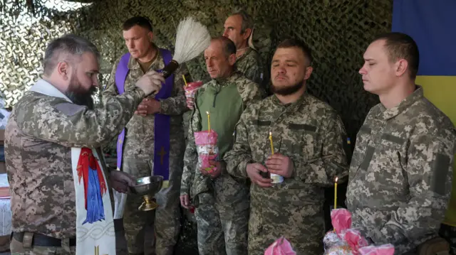 Holy water is sprayed on front line soldiers by a military chaplain