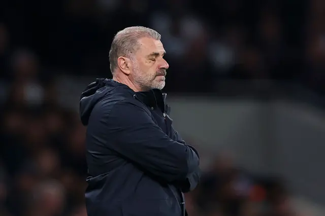 Postecoglou sighs while standing with arms crossed on the touchline