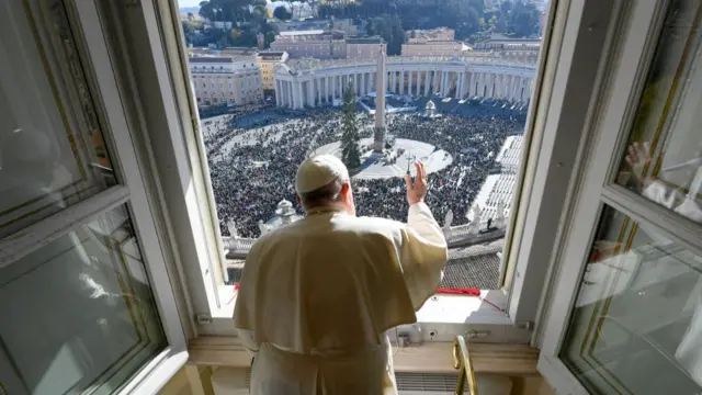 Pope Francis waves from a window to a large crowd below