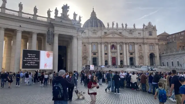 St Peter's Square, with a screen with a photo of the Pope on it and people walking around