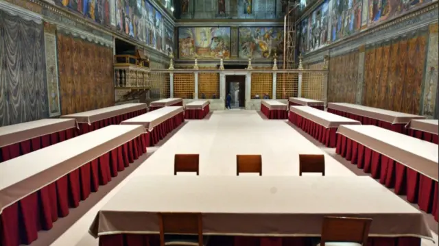 Long tables with red drapes and white tablecloths line the Sistine Chapel