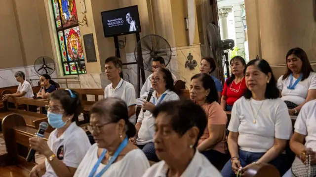 Women sit on pews in a church in prayer.