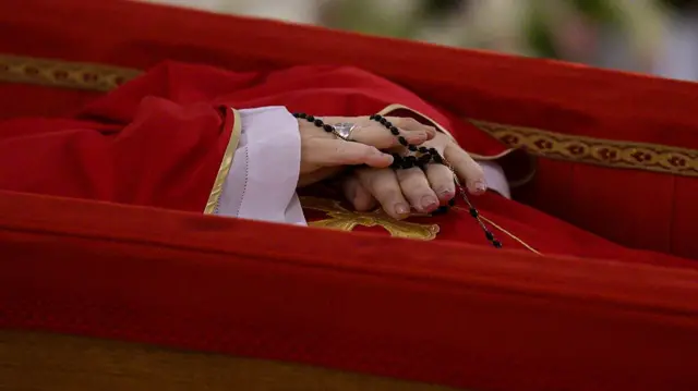 Pope Francis is shown wearing the simple silver ring while lying in an open coffin in the chapel of Casa Santa Marta