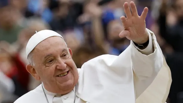 Pope Francis smiling and waving.