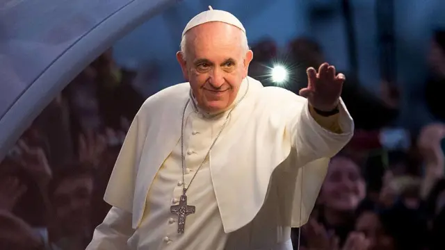 Pope Francis with his hand stretched out waving at crowds
