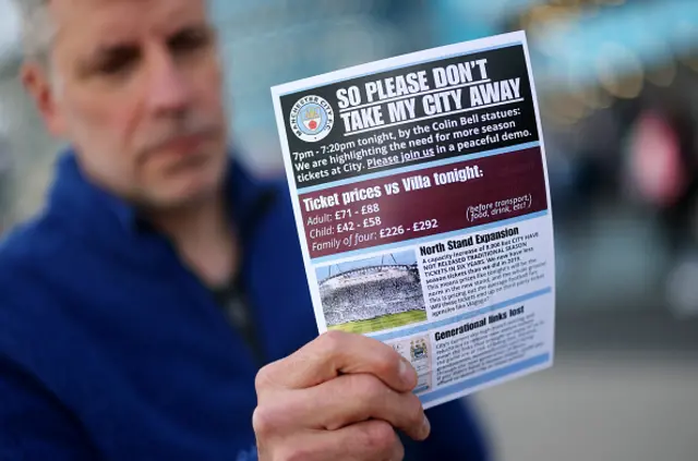 A fan of Manchester City is seen with a flyer containing information regarding a fan protest
