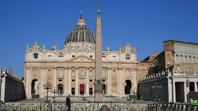 A general view shows St Peter's basilica in the early hours of the morning with one lone man walking along metal barriers surrounding the square