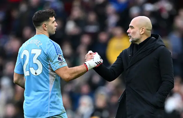 Pep Guardiola, Manager of Manchester City, interacts with Emiliano Martinez