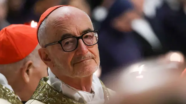 Cardinal Michael Czerny (elderly man with little hair and some beard wearing thick rimmed black glasses) wearing a red skullcap and white and gold vestments
