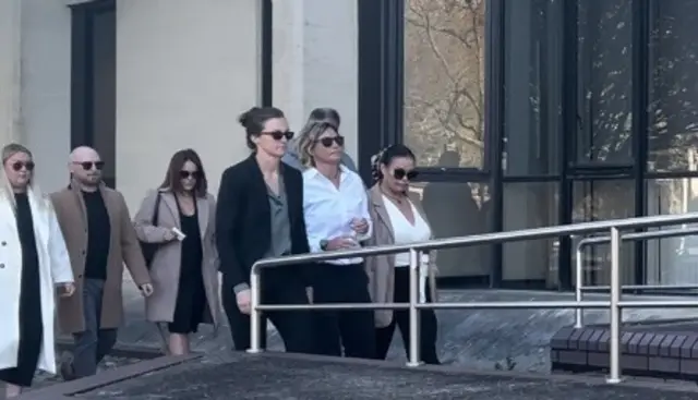 Nerys Lloyd arrives at Swansea Crown Court wearing a white shirt and black sunglasses