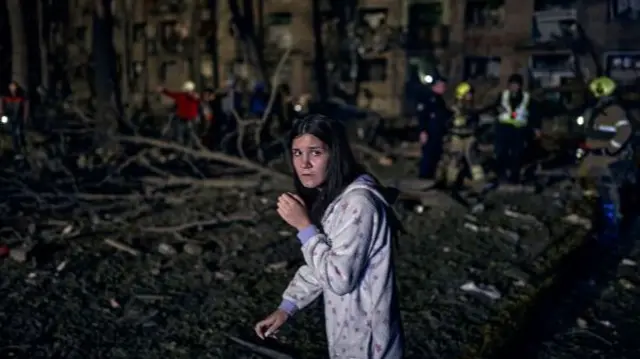 A woman in the ruins of a residential building hit by a Russian strike as rescue workers search for survival in the rubble