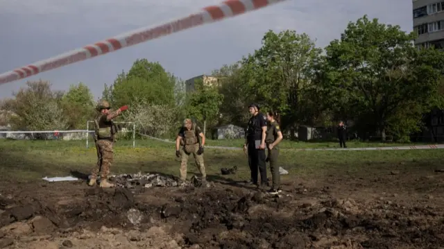 Ukrainian servicemen stand at the site of a missile attack - a red cordon is visible in the frame