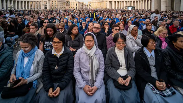 Faithful attend a rosary prayer in suffrage of Pope Francis in St. Peter's Square at the Vatican. The large crowd gather at the Vatican and look ahead.